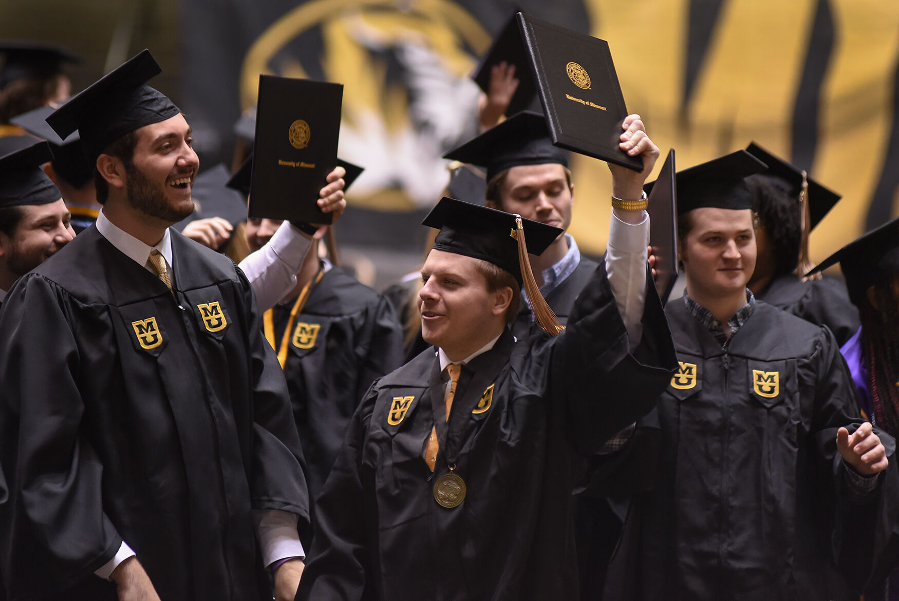 Trulaske College of Business graduates display their diplomas to their families